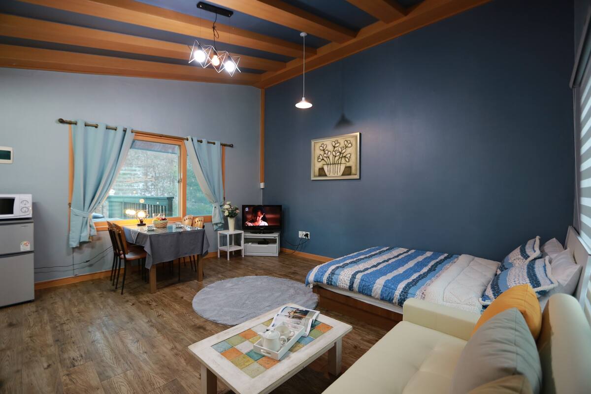 A cozy living room with a sofa, a dining table, and a TV.
