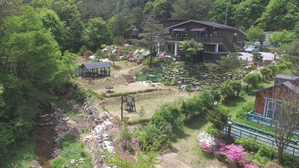 A two-story house with a garden, a swing set, and a small pond. - Tirol Pension (Pyeongchang)