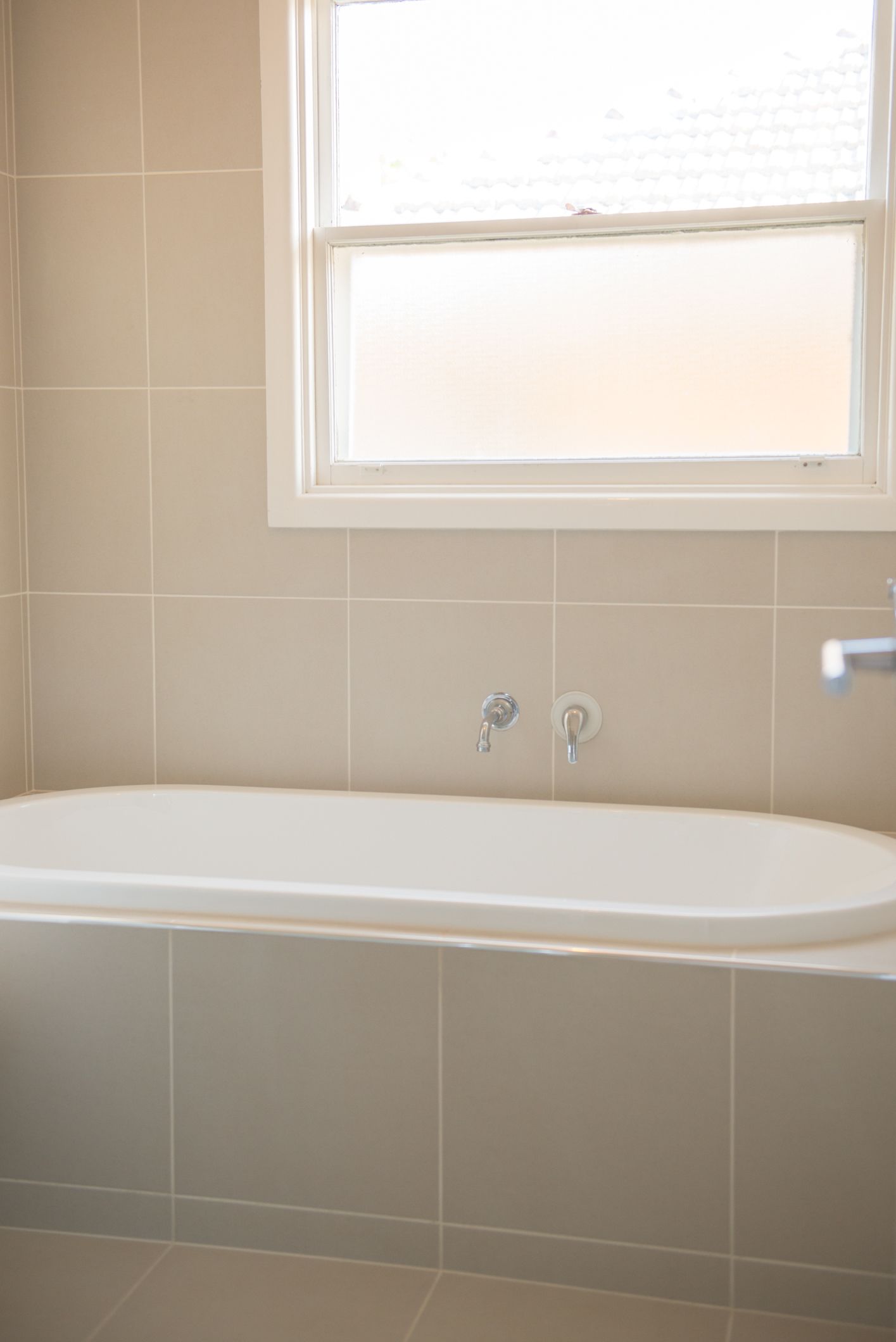Un baño con bañera, ventana y grifo de pared.