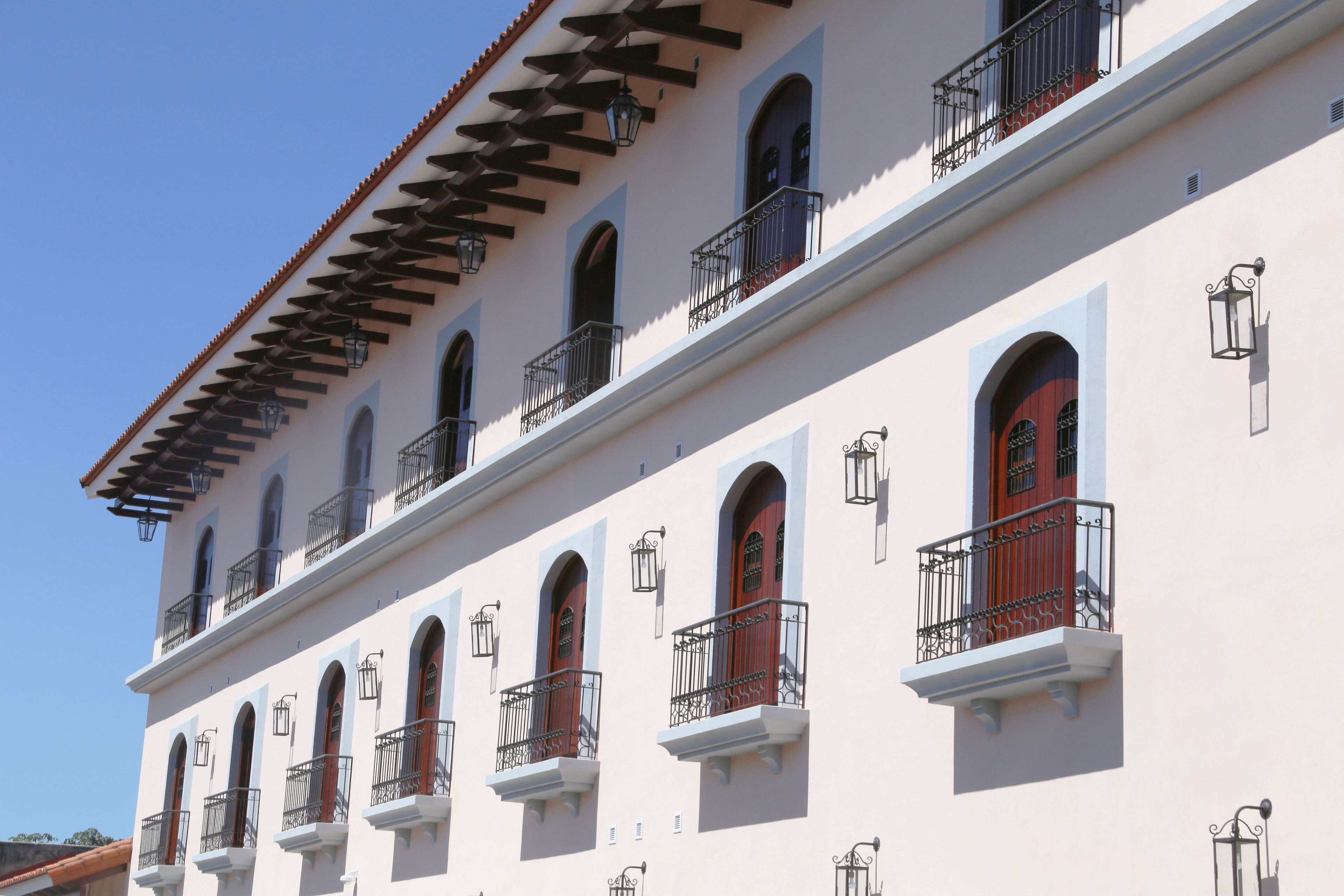 A multi-story building with arched windows, balconies with wrought iron railings, and a series of lantern-style lights.