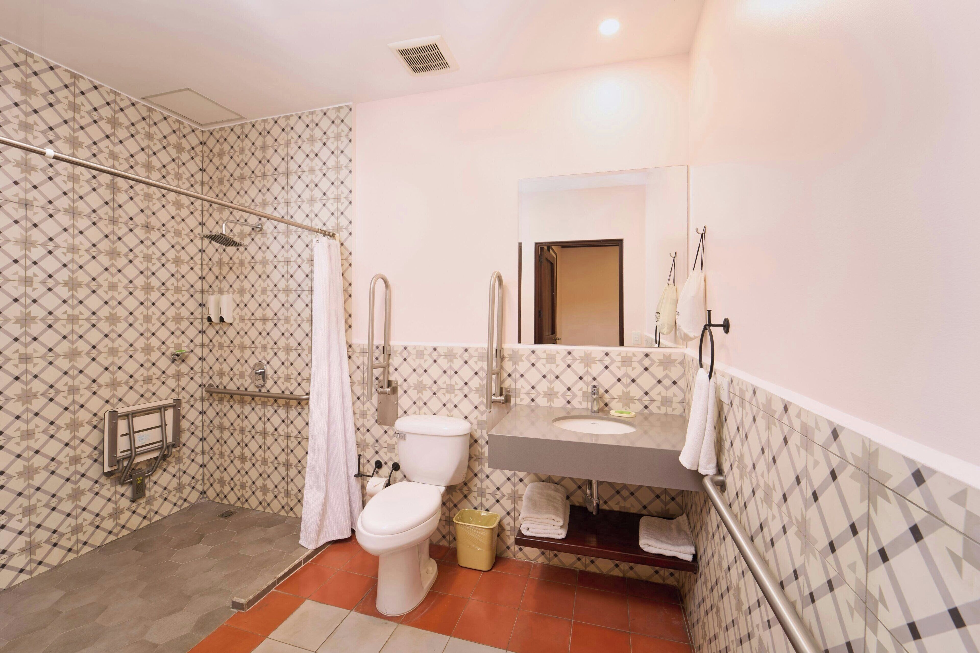 Une salle de bain équipée d’une douche, de toilettes, d’un lavabo et d’un miroir.