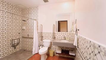 Een badkamer met douche, toilet, wastafel en een spiegel.