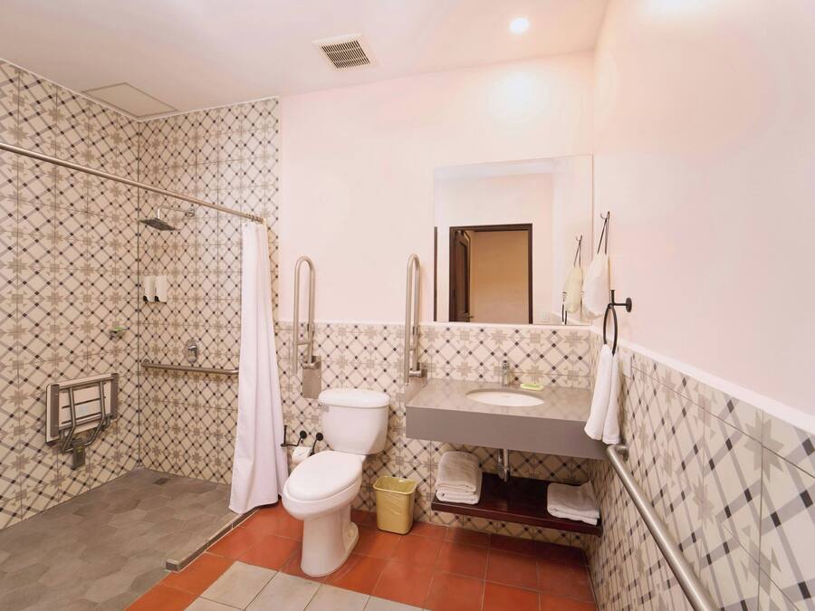 Een badkamer met douche, toilet, wastafel en een spiegel.
