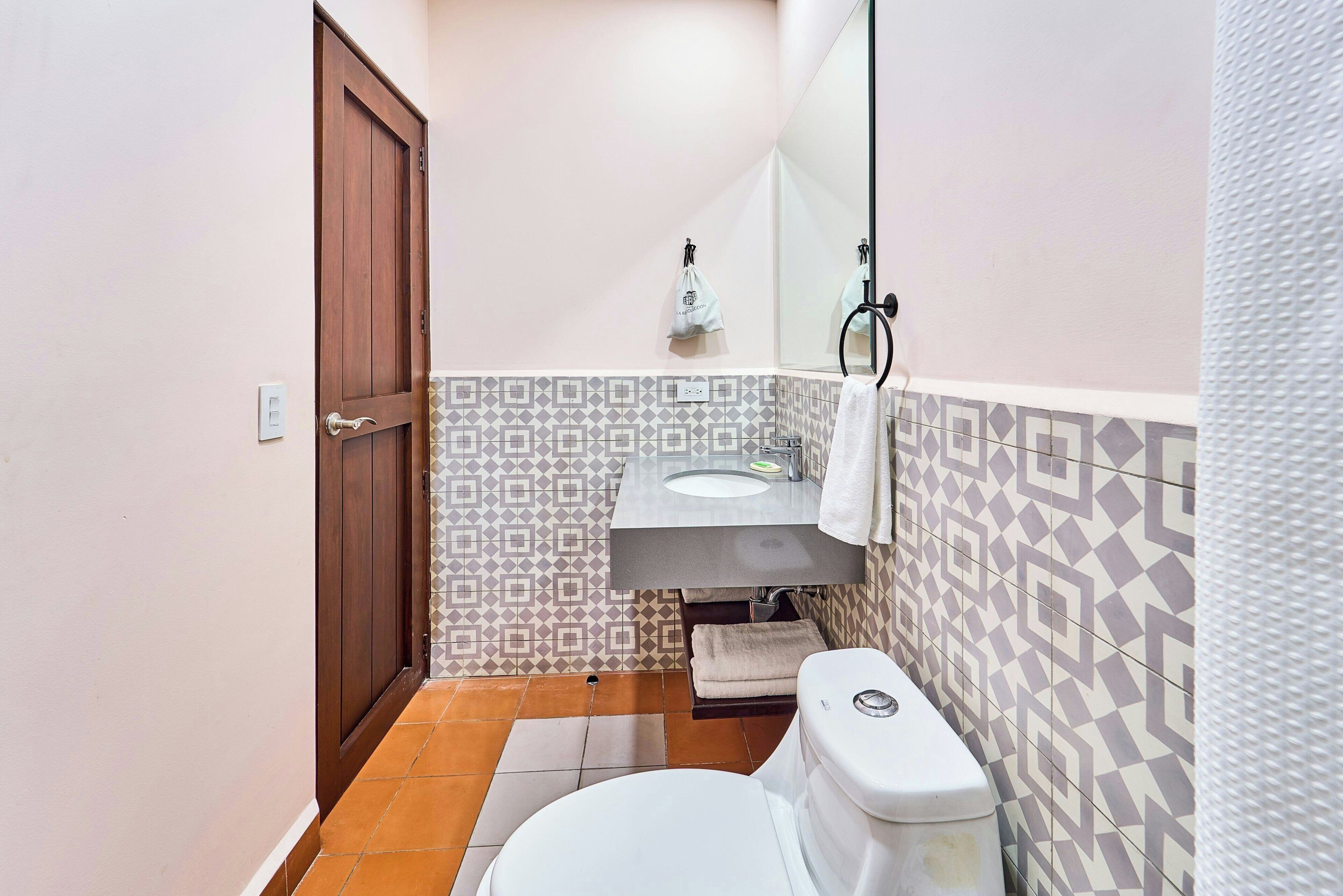 A bathroom with a toilet, sink, and mirror.