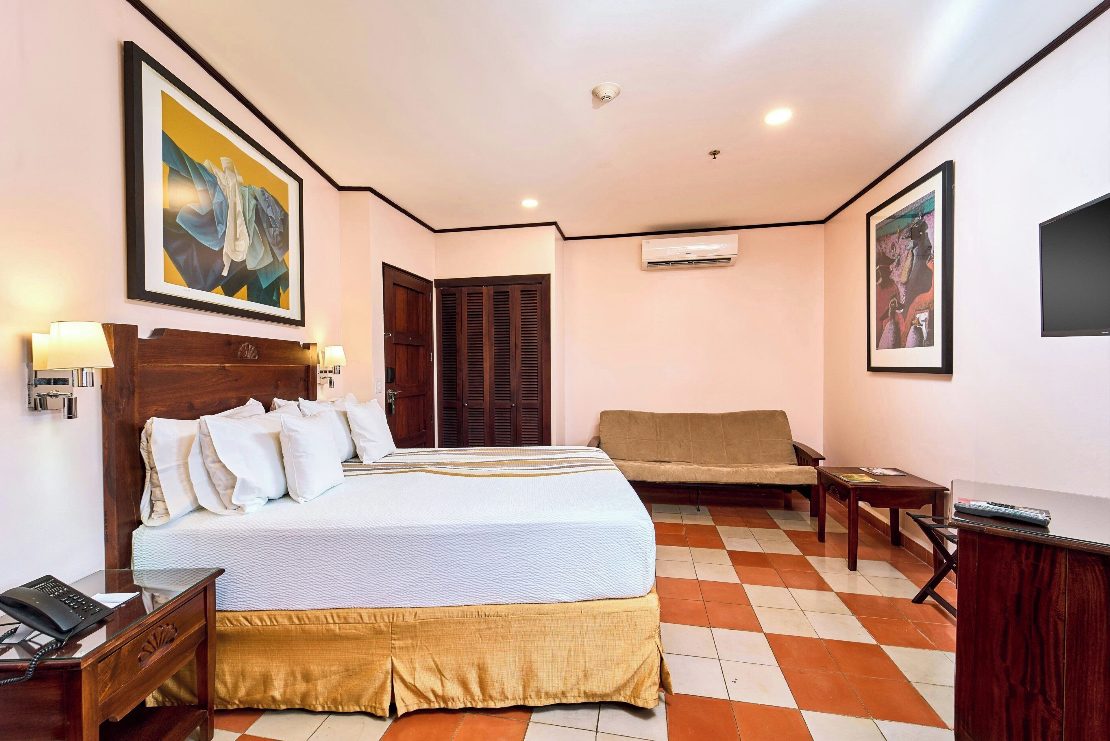 Una habitación de hotel con cama, sofá, escritorio y una silla.