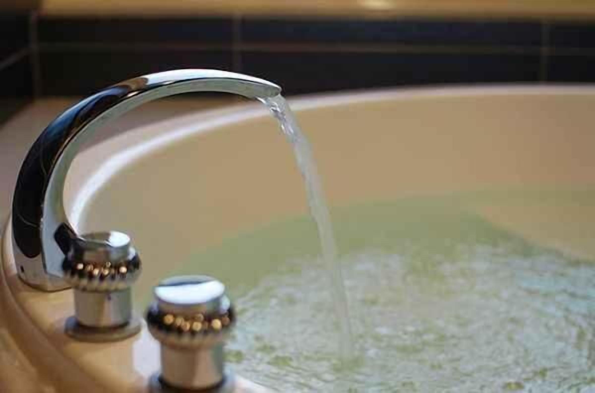 A bathroom with a modern faucet and a bathtub filled with water.