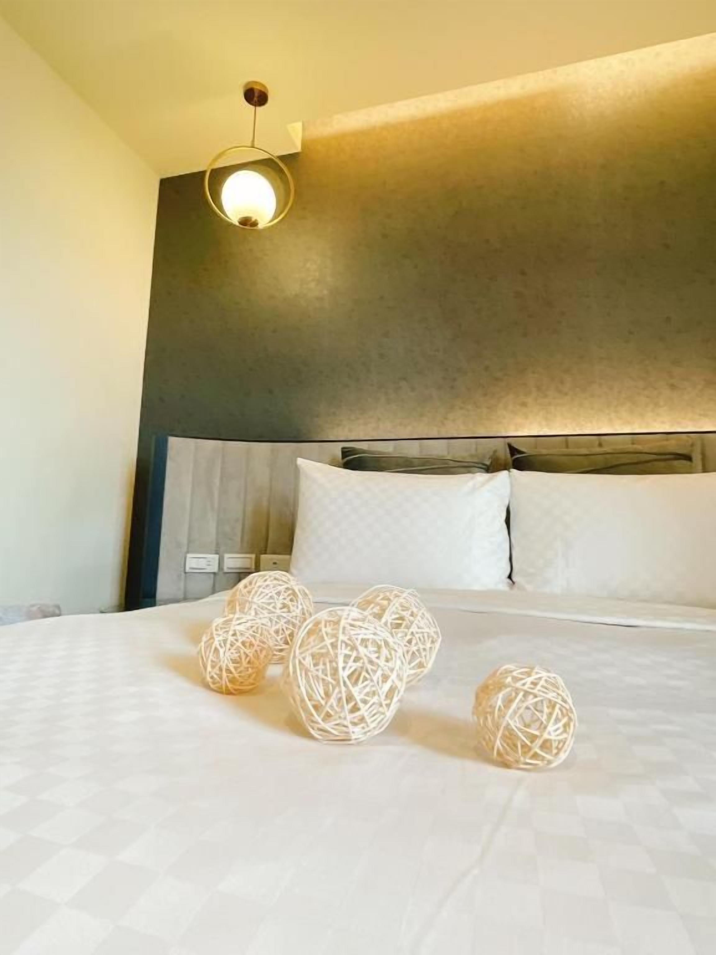 Una habitación de hotel con una cama, lámparas de noche y un cabecero.