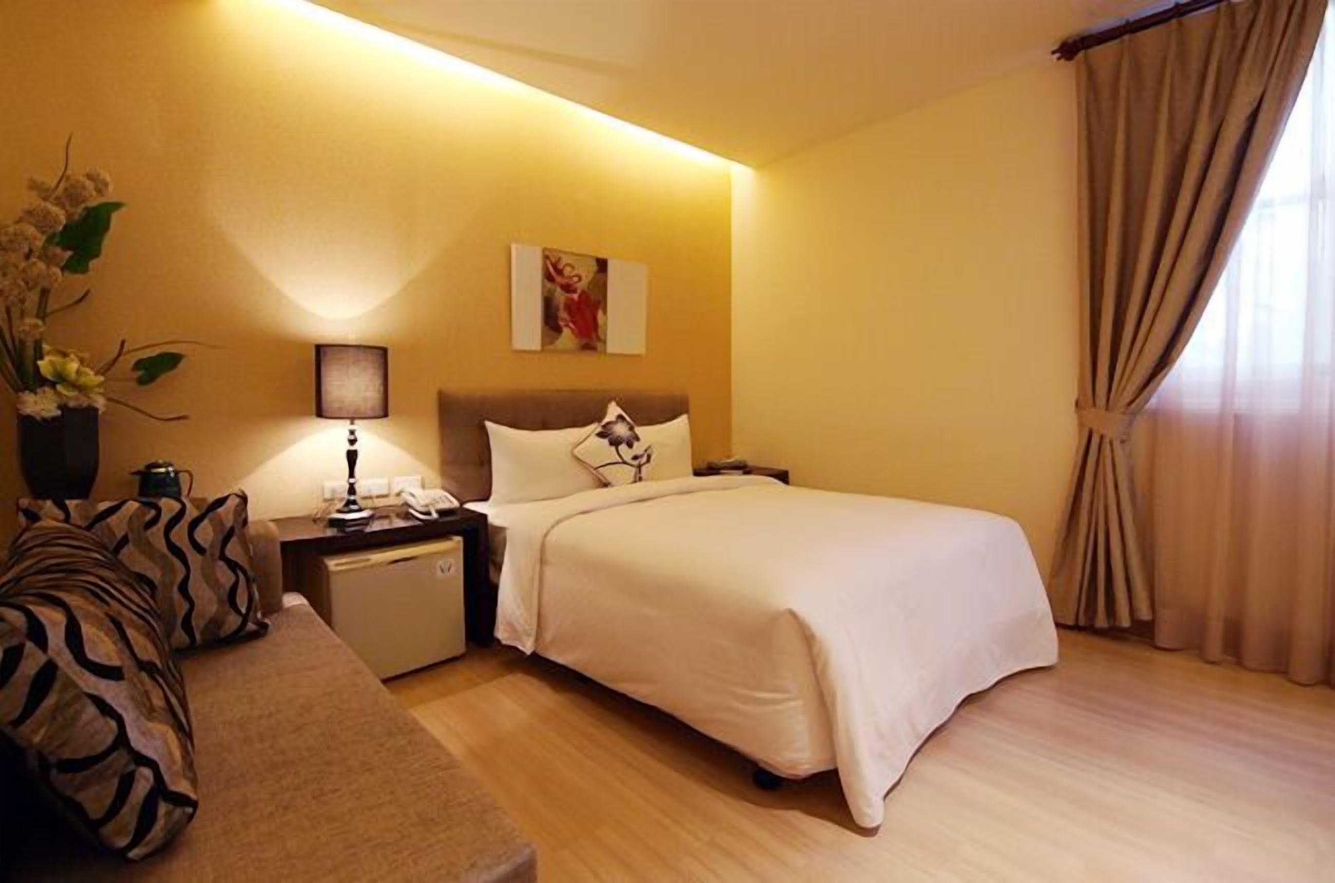 Habitación de hotel con cama, mesita de noche, lámpara y un cuadro en la pared.