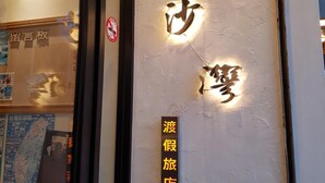 Une façade d’immeuble ornée de caractères chinois illuminés et d’une enseigne indiquant une agence de voyages.