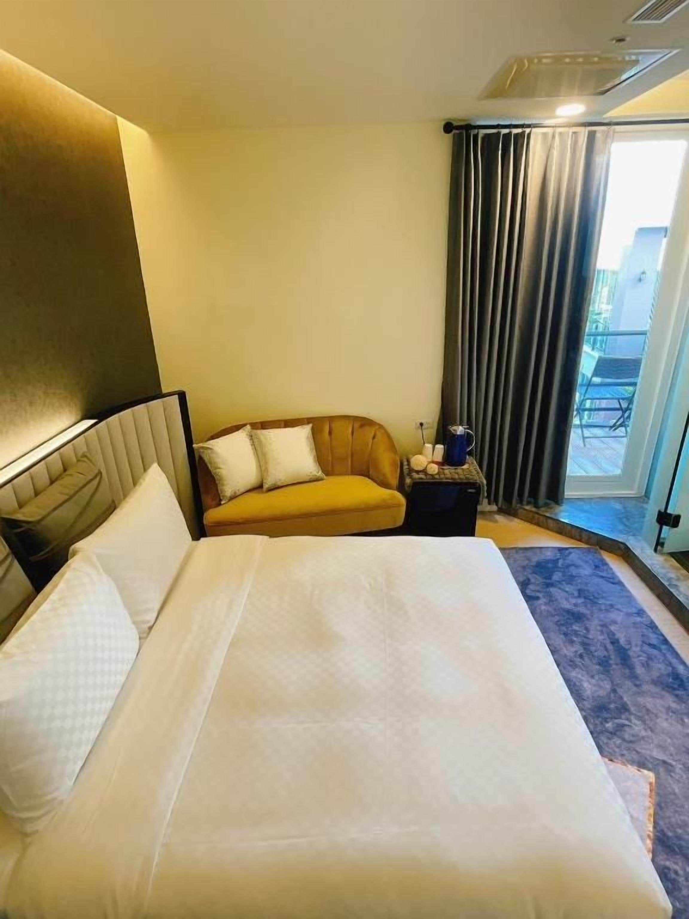 Hotellihuone, jossa on suuri sänky, sohva, pieni pöytä ja ikkunasta avautuva näkymä ulos.