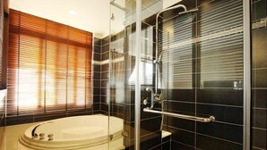 Une salle de bain moderne avec une baignoire, une cabine de douche en verre et des murs recouverts de carreaux foncés.