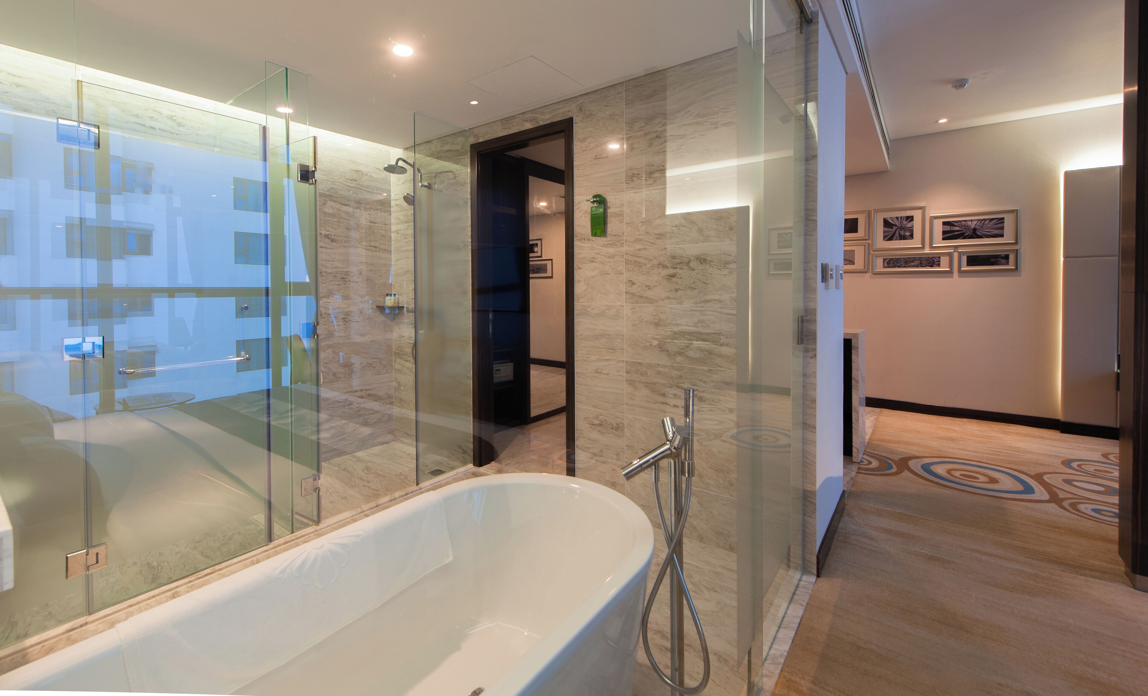 A modern bathroom with a freestanding bathtub, glass shower enclosure, and marble walls.