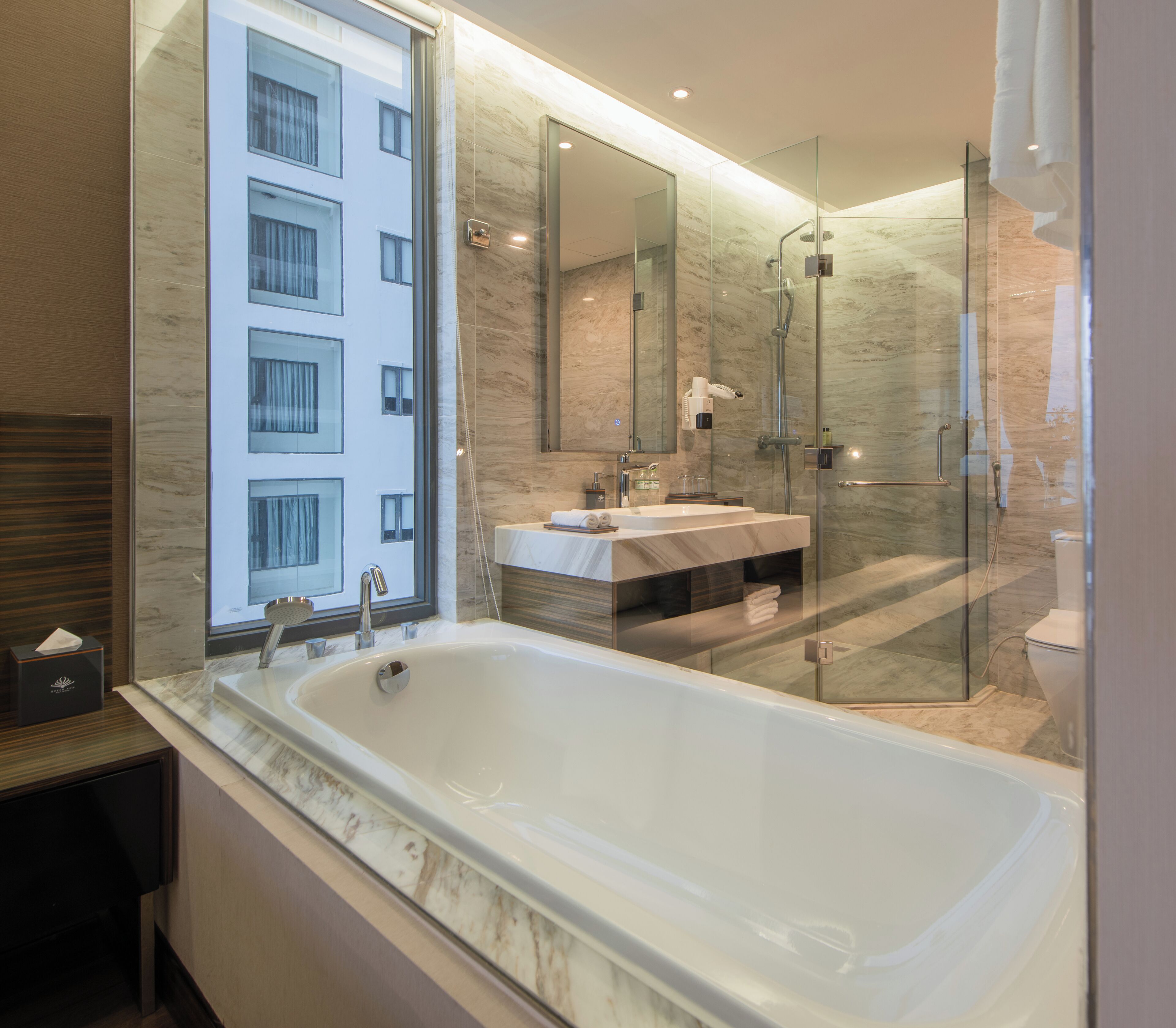 Une salle de bain moderne dotée d’une grande baignoire, d’une douche à parois de verre et d’un meuble-lavabo avec un miroir.