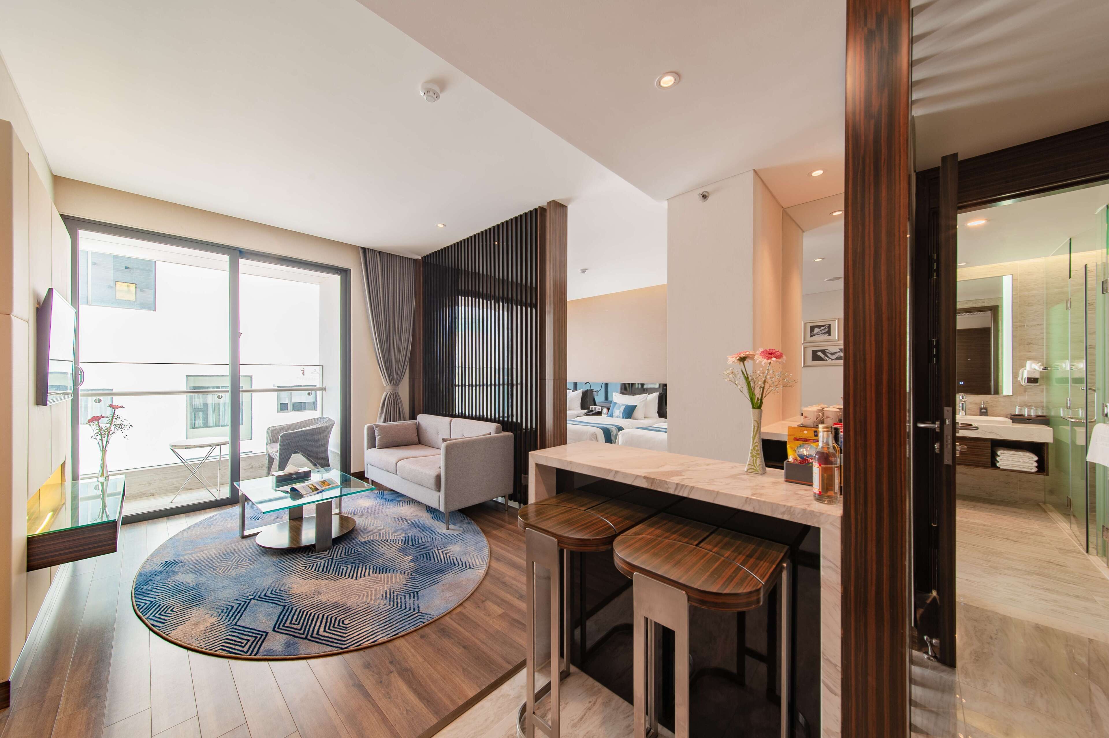 Una sala de estar moderna con una mesa de centro de vidrio, un sofá y un comedor con taburetes de bar.