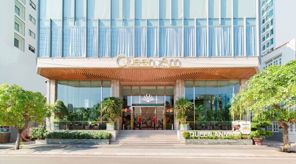 Welcome to the Queen Ann Hotel, featuring a modern design with a large entrance and beautiful landscaping.