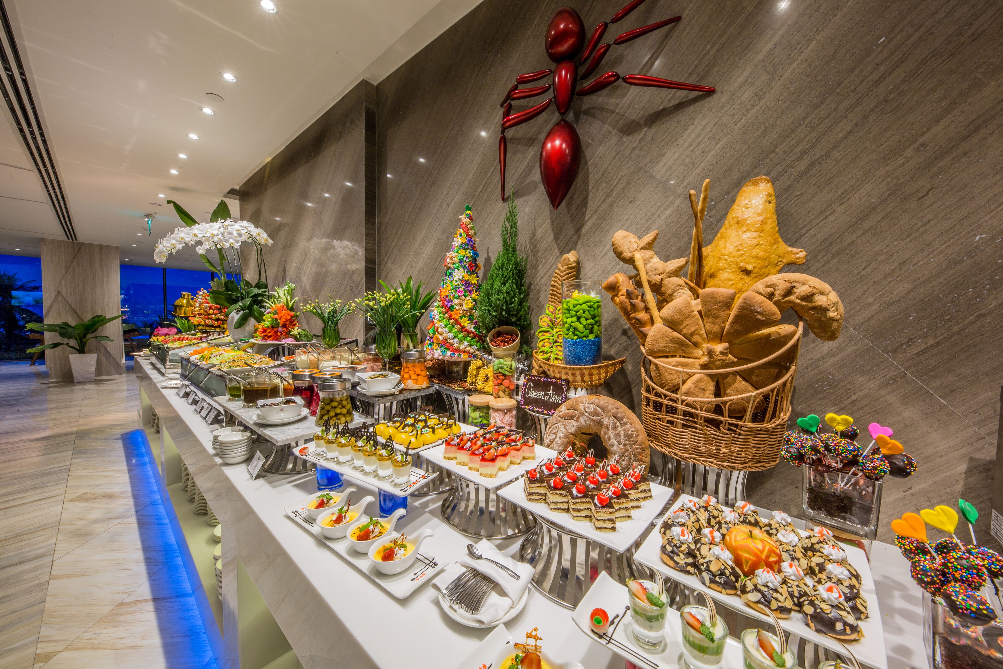 A buffet with various food items and a decorative spider on the wall.