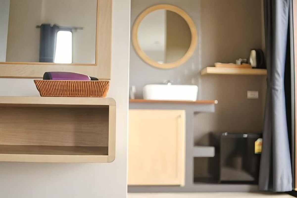 Un baño con estante de madera, una cesta, un espejo y un lavabo.