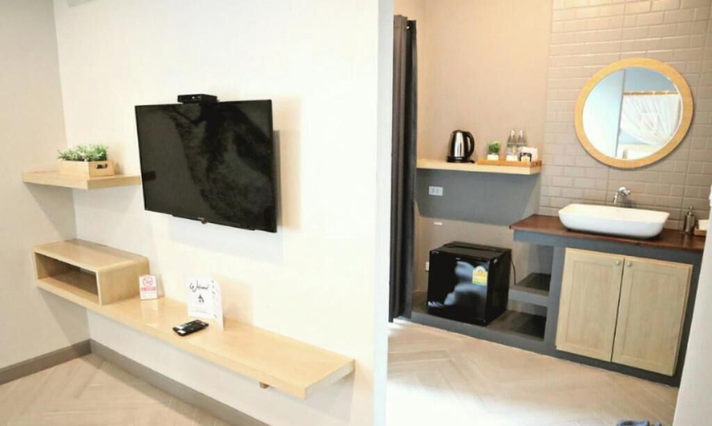 A modern bathroom with a built-in sink, a round mirror, and a television mounted on the wall.