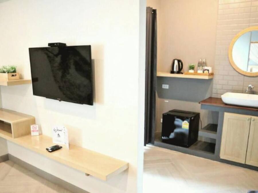 A modern bathroom with a built-in sink, a round mirror, and a television mounted on the wall.