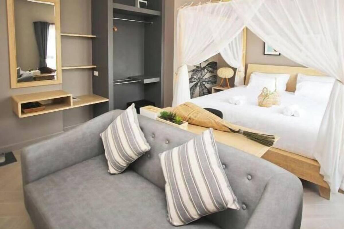 Ein modernes Schlafzimmer mit einem Bett, einem grauen Sofa und einem Nachttisch.
