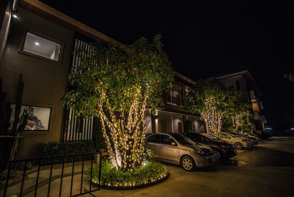 A parking lot with cars and illuminated trees at night.