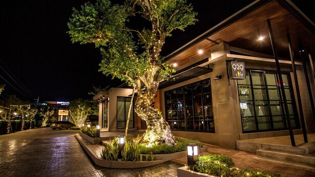 A modern building with a cafe sign, a tree with lights, and a paved entrance. - Bunprasop Garden Hotel (Nakhon Si Thammarat)