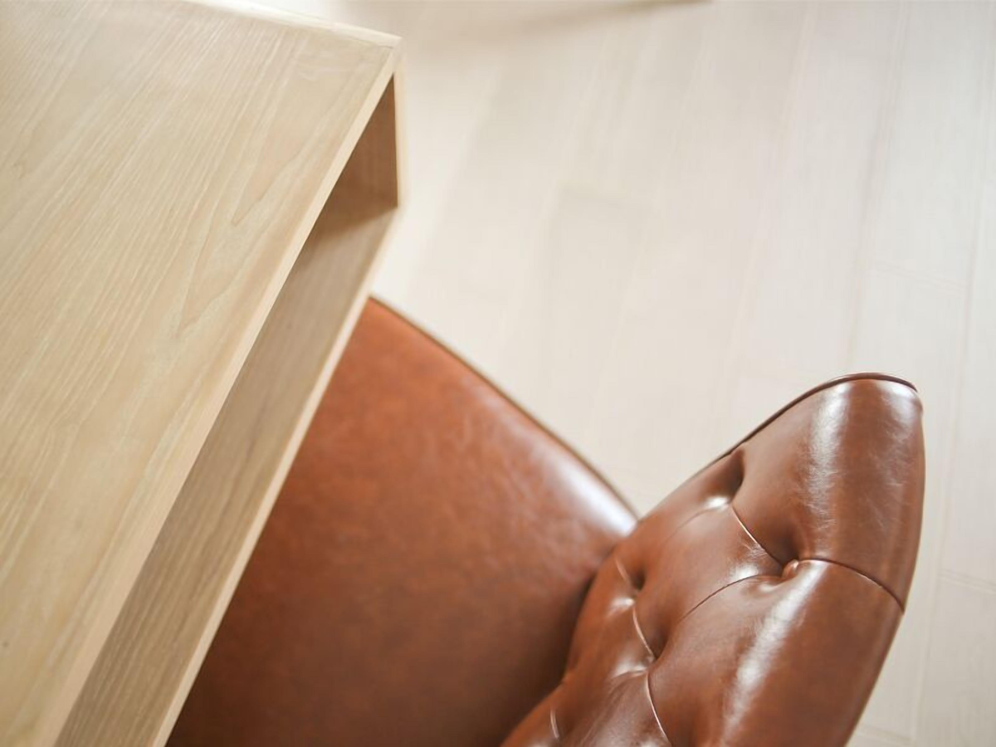 A brown leather armchair with a high backrest and a cushioned seat, positioned against a light-colored wall.
