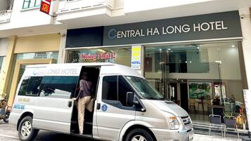 A shuttle bus with a sign for 'Thong Nhat 2 Hotel' and a building labeled 'Central Ha Long Hotel' in the background.