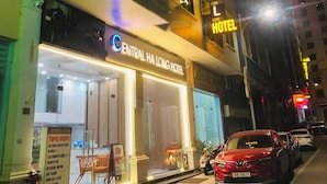 La façade de l'hôtel Central Ha Long, avec son enseigne lumineuse, son entrée bien visible et une voiture garée devant.