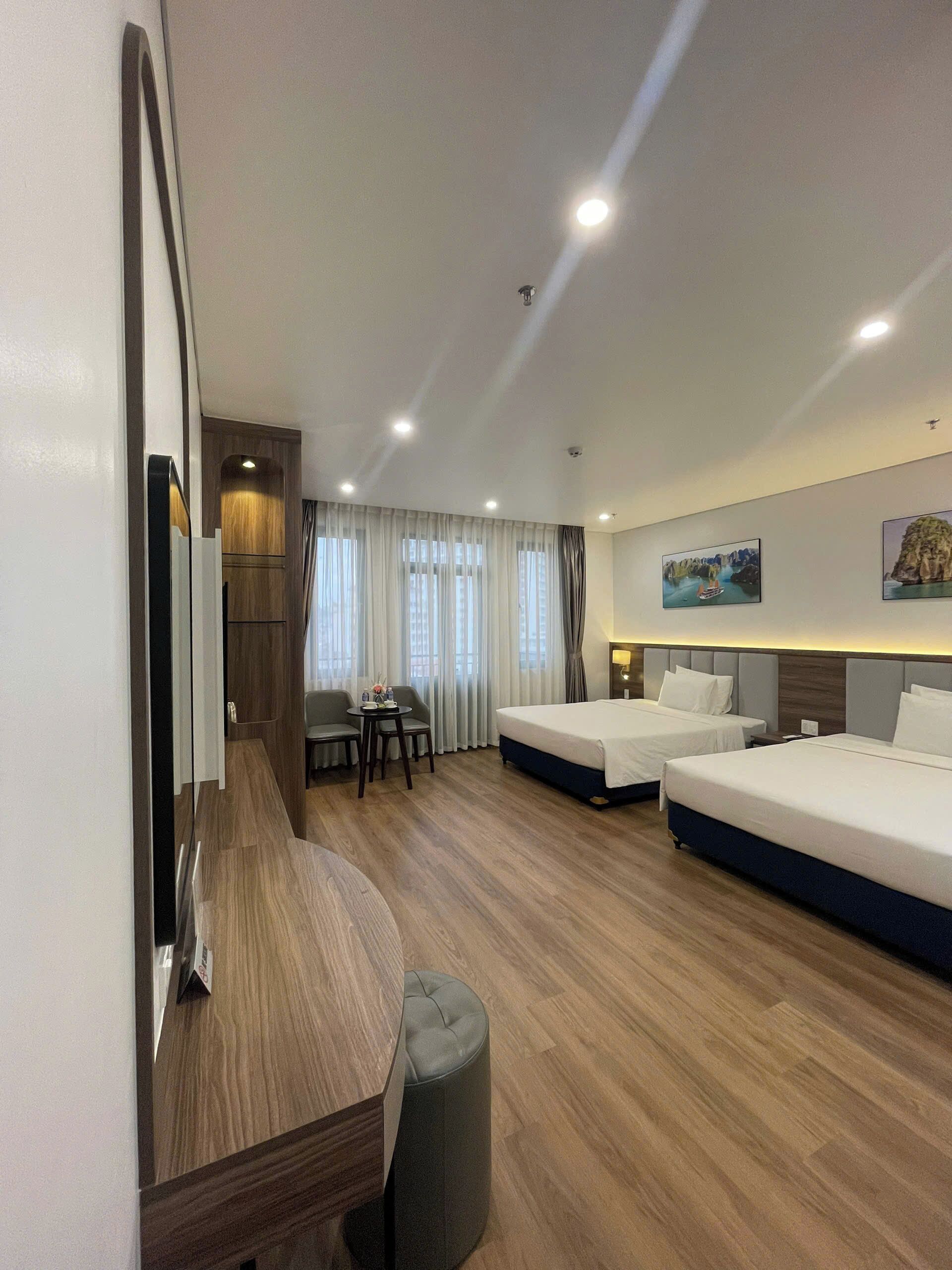 Una habitación de hotel con dos camas, un escritorio, una silla y un espejo grande.