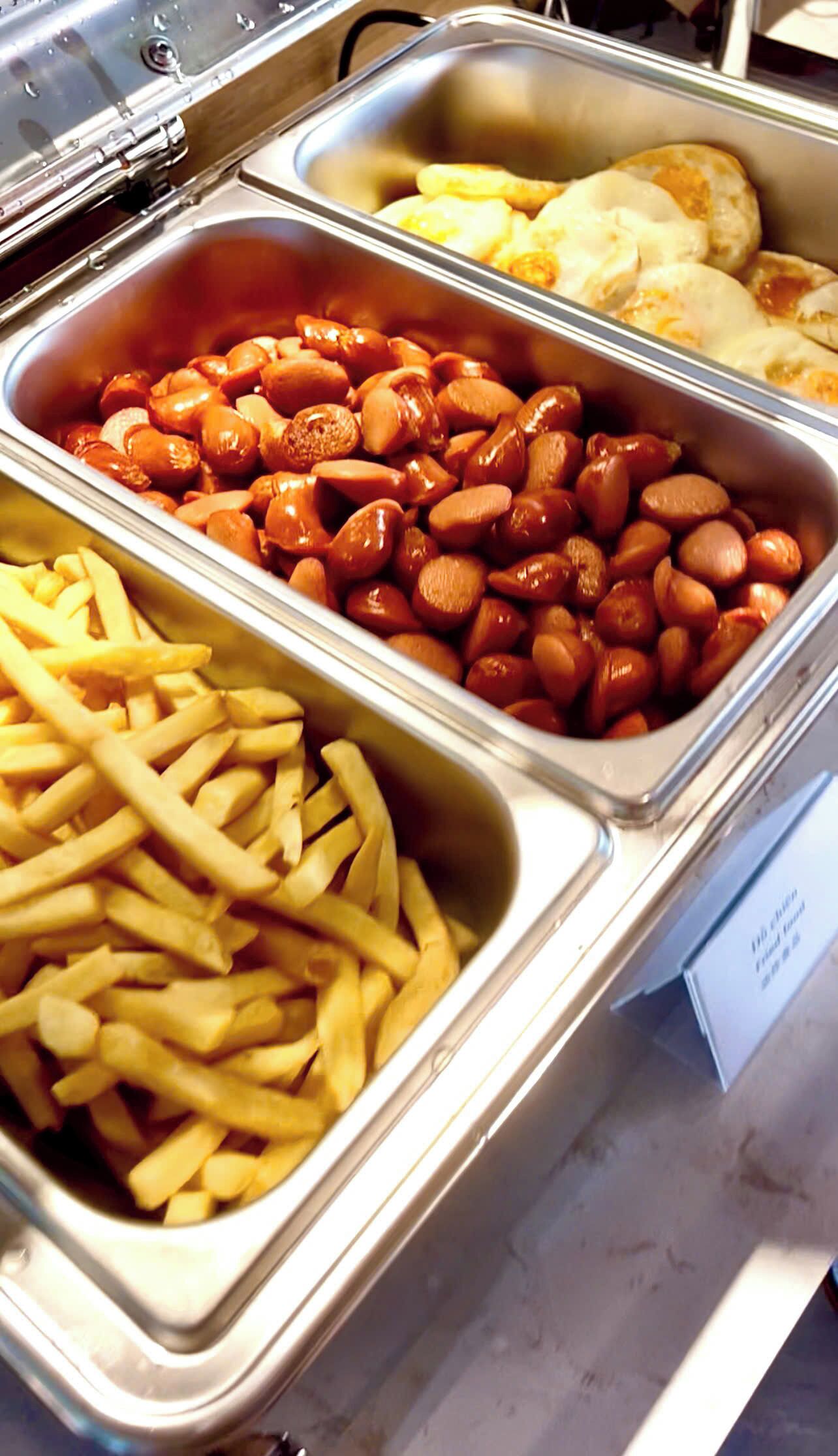 A buffet with French fries, roasted beans, and baked items.