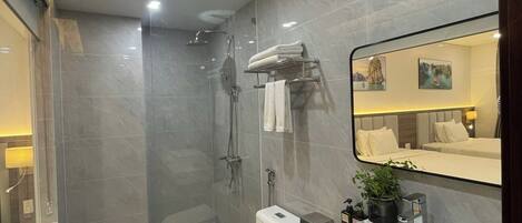 A modern bathroom with a glass-enclosed shower, a white toilet, a vanity with a sink, and a mirror.
