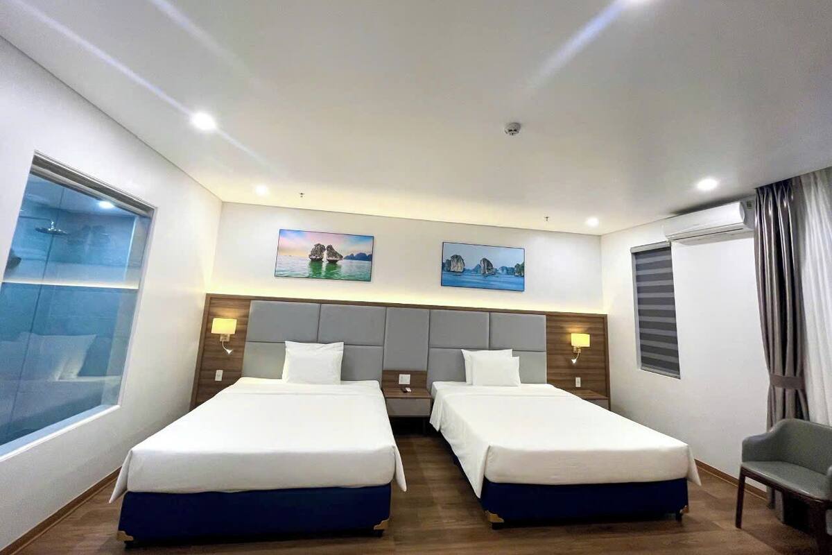Habitación de hotel con dos camas, un ventanal con vistas y obras de arte en la pared.