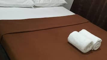 Un lit bien fait, avec des draps blancs et une couverture marron.