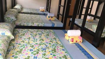 A bunk bed with floral bedding and a small table with a yellow plush toy.