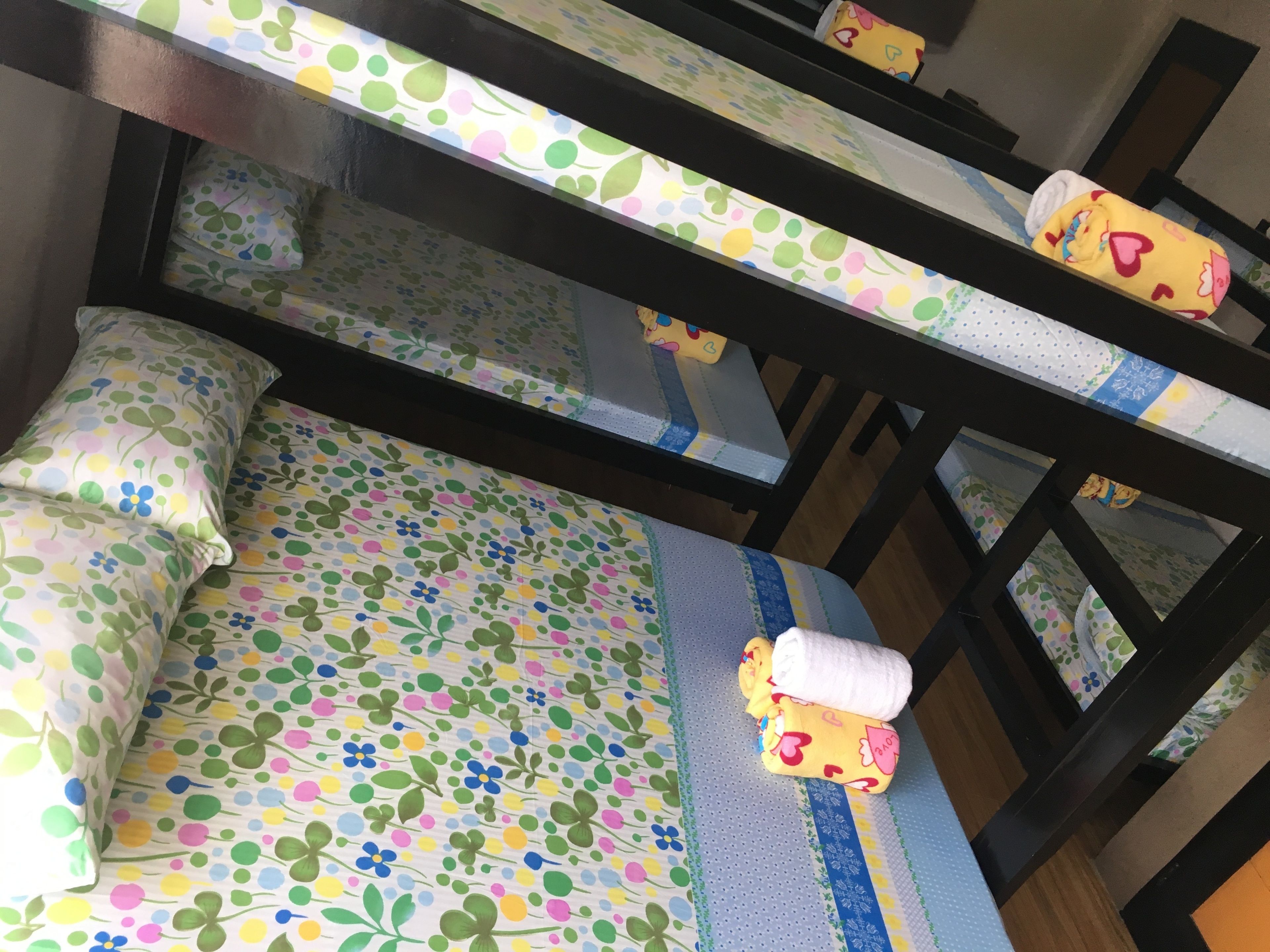 A bunk bed with floral-patterned bedding and a rolled-up towel on the lower bunk.