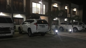 A parking area with several white SUVs parked in front of a building with balconies and large windows.