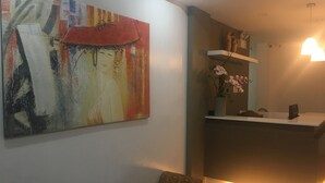 A modern interior with a large abstract painting, a reception desk, and a patterned armchair.