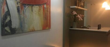 A modern interior with a large abstract painting, a reception desk, and a patterned armchair.