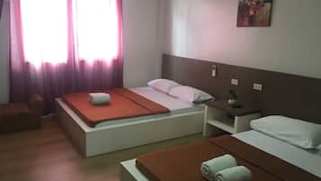 Una habitación de hotel con dos camas, una mesita de noche con una planta, una pequeña silla y un cuadro en la pared.
