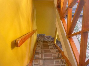 A staircase with a wooden handrail and patterned floor tiles.