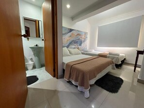 Un dormitorio moderno con una cama grande, una mesita de noche, un espejo y un baño con lavamanos y lavadora.