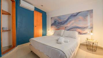 Een slaapkamer met een bed, een houten garderobe, een airconditioningapparaat, een schilderij aan de muur en een nachtkastje met een lamp.