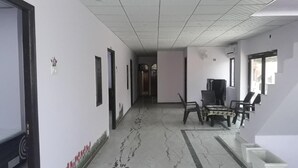 Um corredor com chão de azulejos, quadros nas paredes e uma escada com cadeira e mesa.