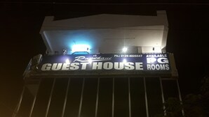 Um edifício com uma placa anunciando "GUEST HOUSE ROOMS" e um número de telefone.