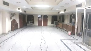 Um quarto amplo com piso de mármore, um balcão de recepção e uma grande porta em arco.
