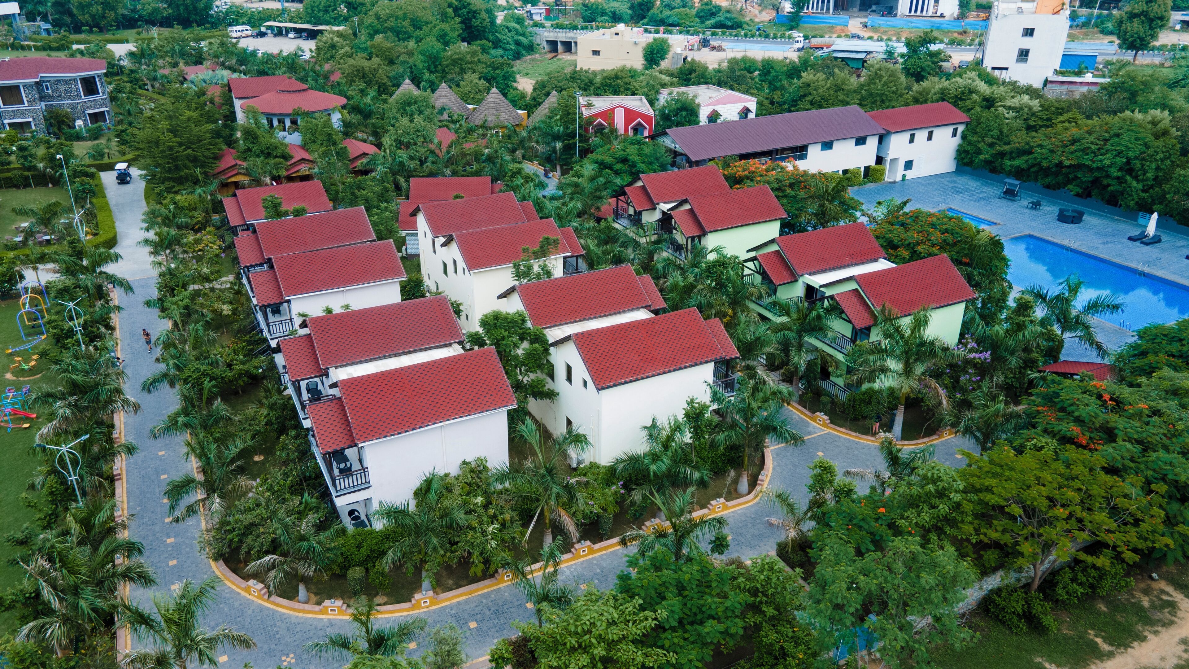 A residential area with multiple houses, a swimming pool, and a road.