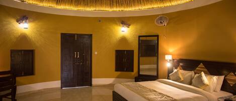 A hotel room with a large bed, a ceiling fan, and a wall-mounted mirror.