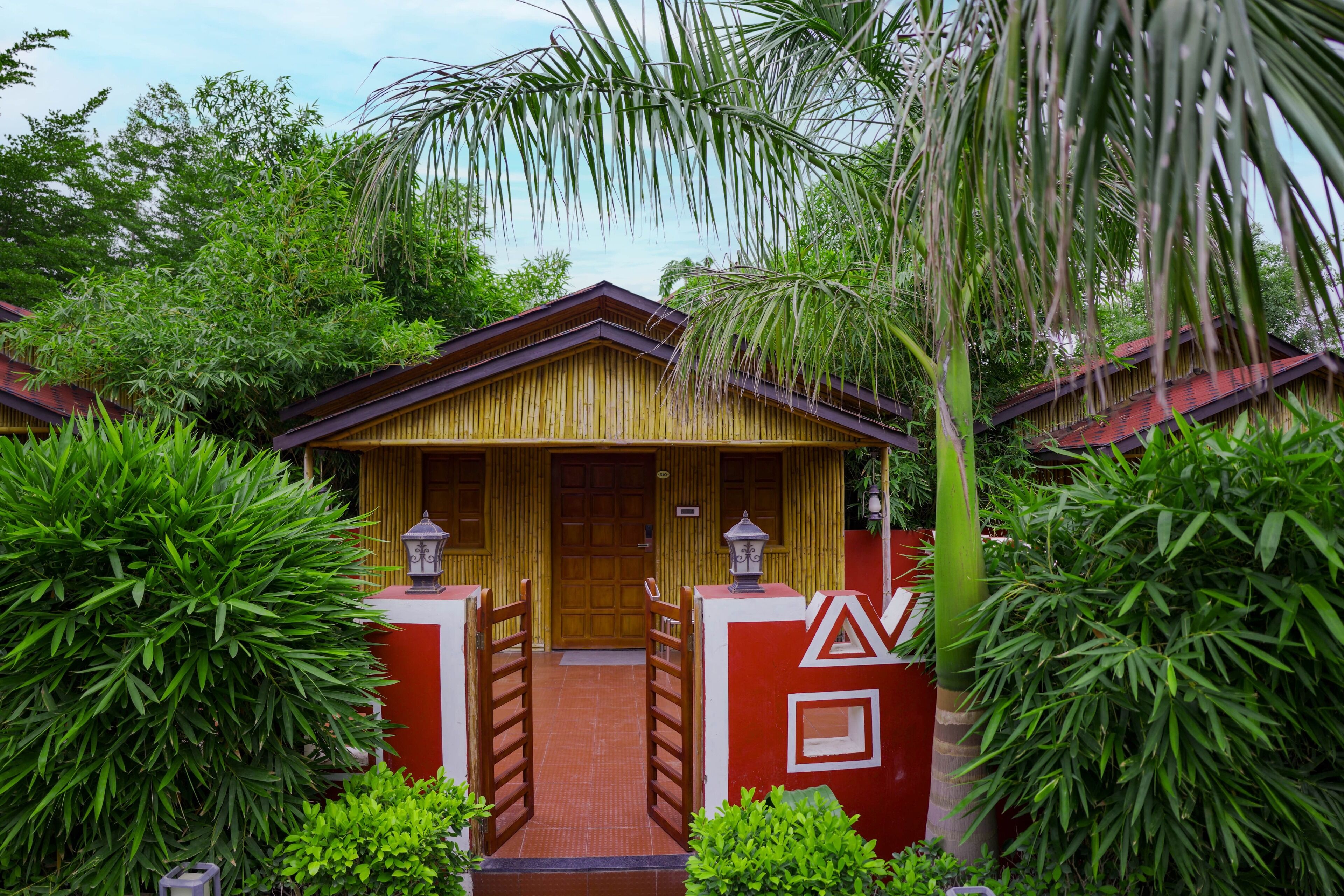 A traditional wooden building with a red and yellow facade, surrounded by lush greenery.