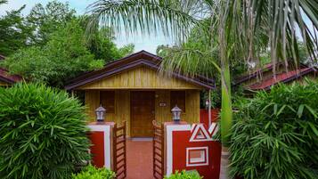 A traditional wooden building with a red and yellow facade, surrounded by lush greenery.